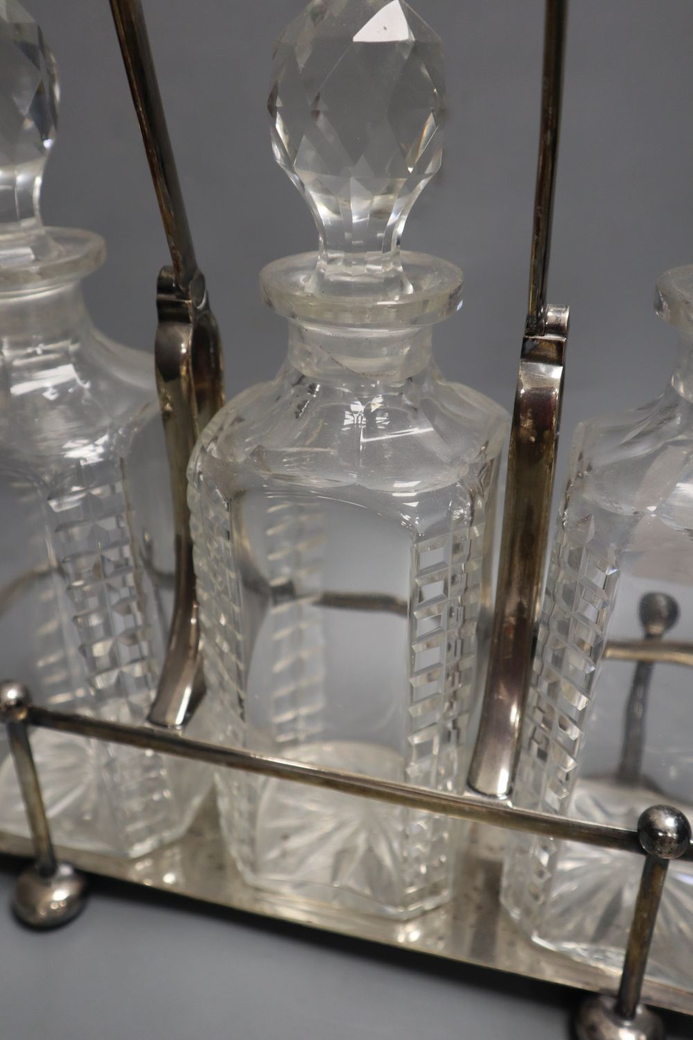 A late 19th century combination desk timepiece / inkwell, hinged timepiece on cut glass well, together with a three decanter tantalus